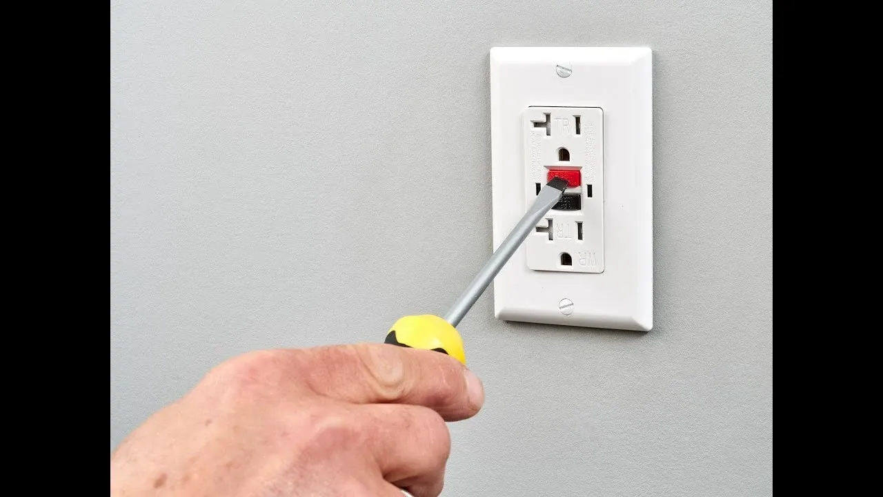 Electrician pressing the reset button on a white GFCI outlet with TEST and RESET buttons