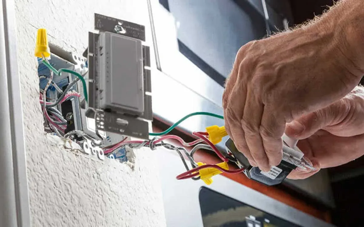 Electrician checking wire connections behind a wall switch in a home
