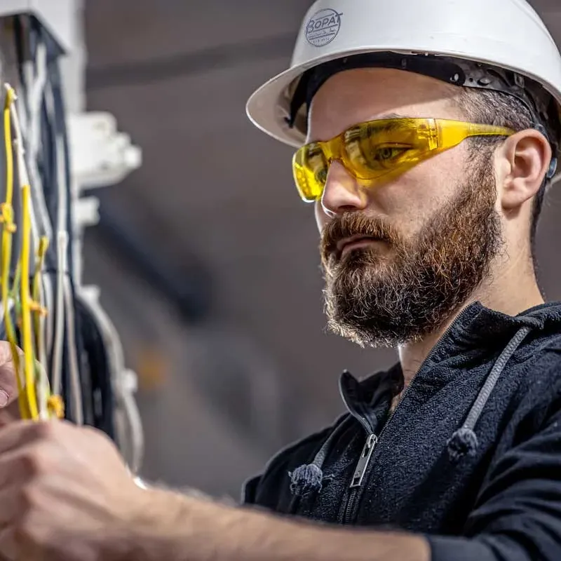 Emergency electrician in a hard hat and safety glasses repairing wiring