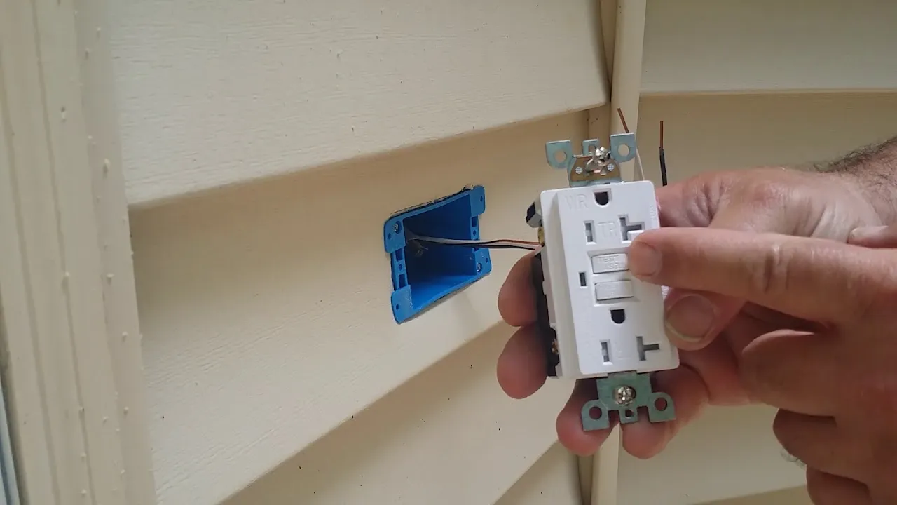 Electrician installing a weather resistant GFCI outlet in a new outdoor box on vinyl siding