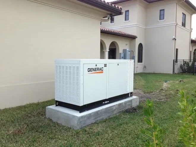 Home standby generator installed on a concrete pad beside a house