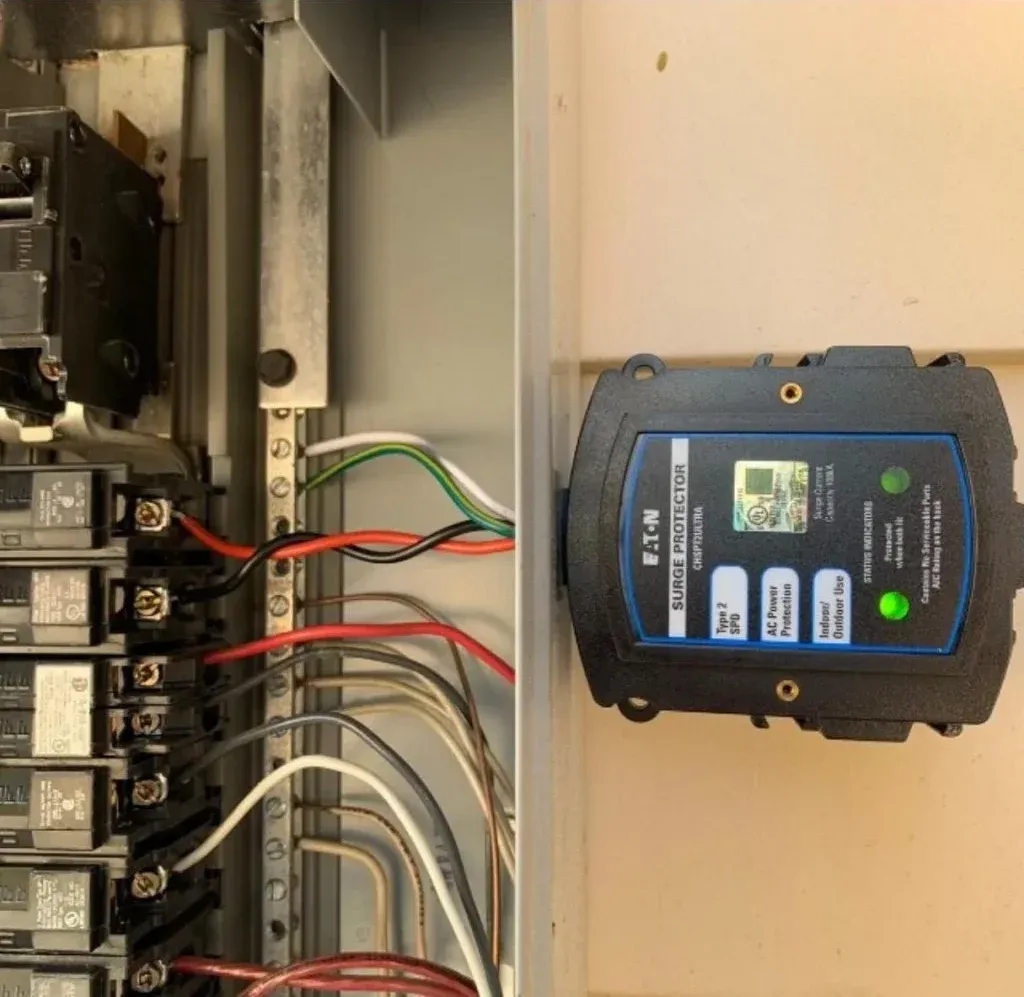 Whole home surge protector mounted beside a breaker panel with both green status lights on