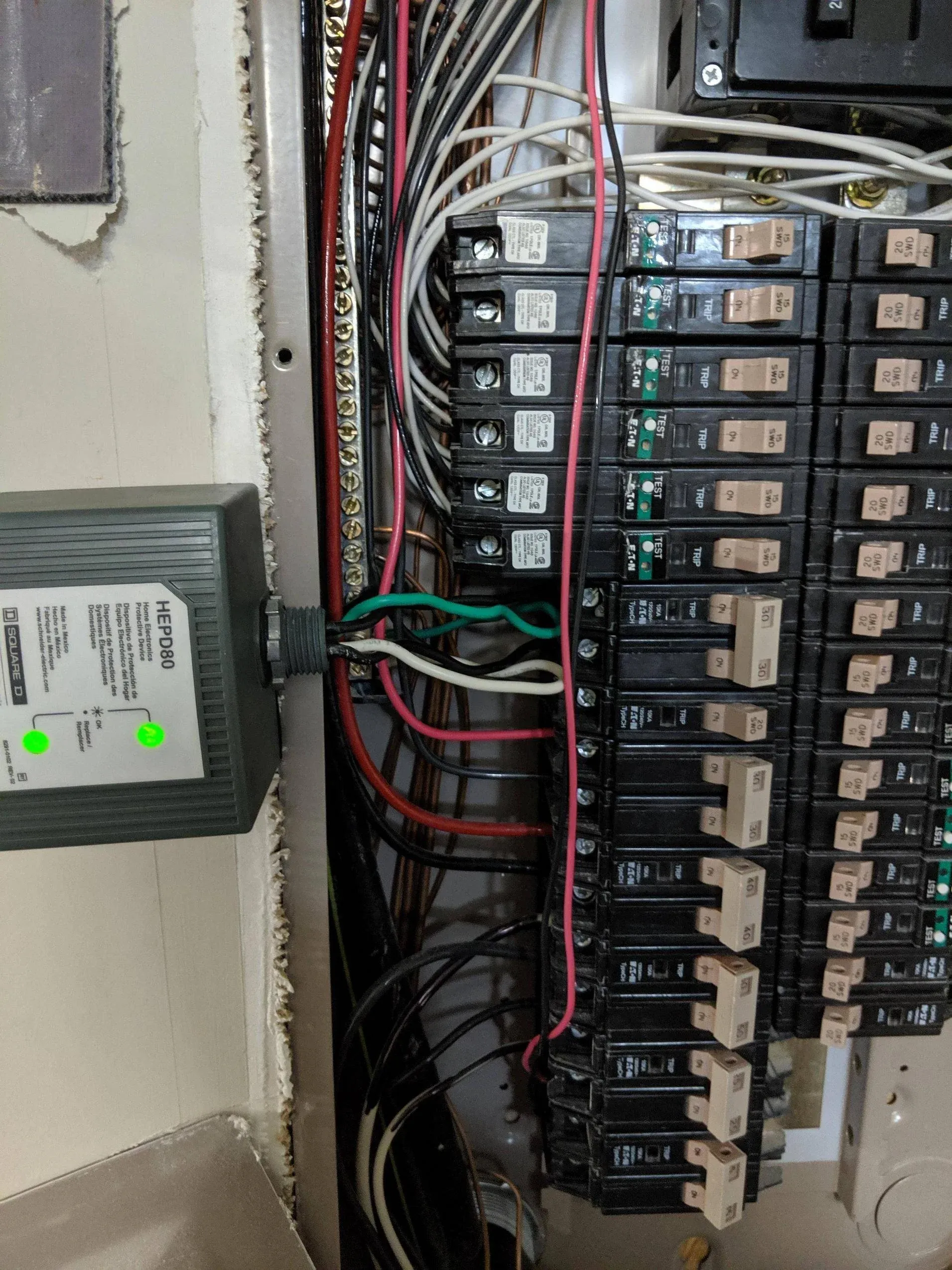 Whole home surge protector with green status lights wired into a breaker panel